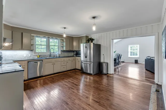 a kitchen with stainless steel appliances a refrigerator and wooden floors