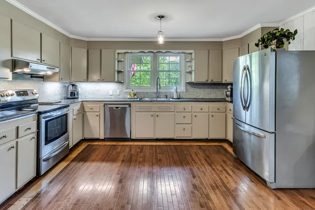 a kitchen with wooden floors and stainless steel appliances