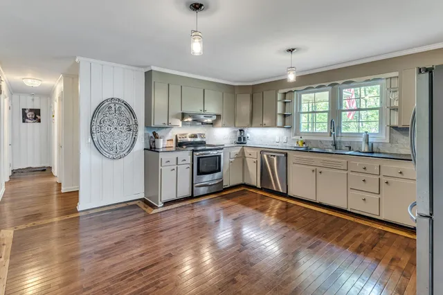 a large kitchen with stainless steel appliances granite countertop a stove and a large window