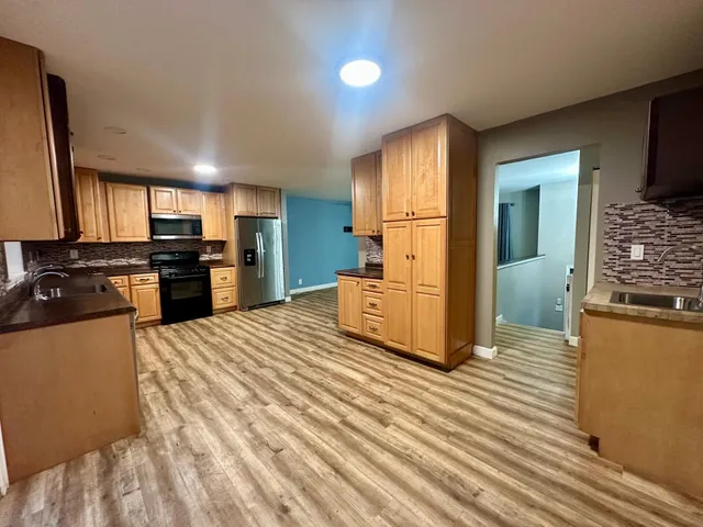 a kitchen with stainless steel appliances kitchen island granite countertop a refrigerator and a stove top oven