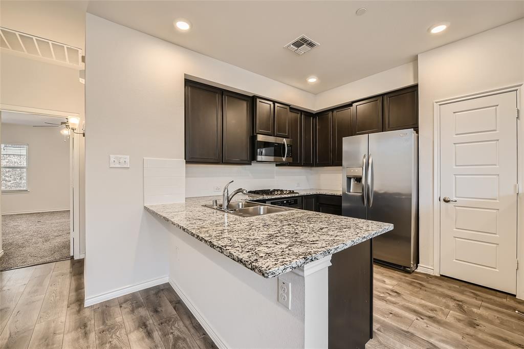 2407 Siskiyou Street Lewisville, TX 75056 - Photo 11 of 31 a kitchen with a refrigerator a sink and wooden cabinets