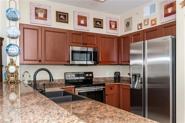 a kitchen with stainless steel appliances granite countertop a refrigerator a stove a sink and a microwave