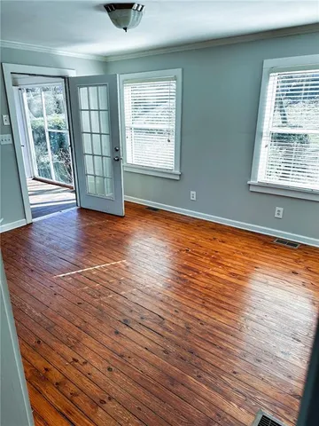 an empty room with wooden floor and windows