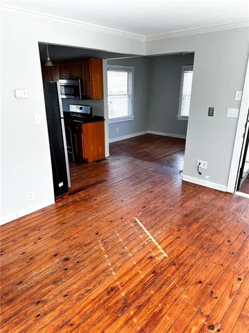 an empty room with kitchen appliances and wooden floor
