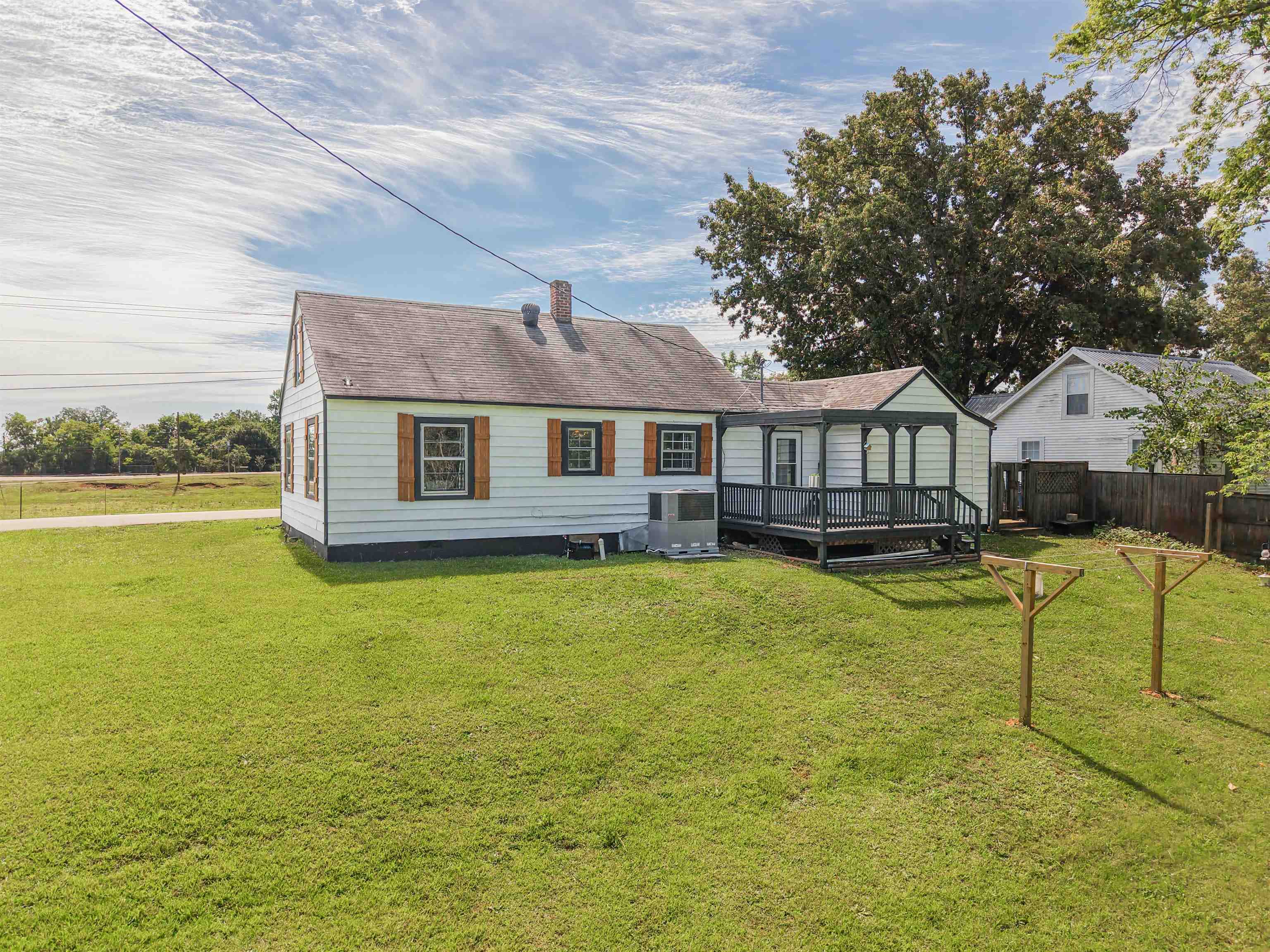 201 Walnut Street Adamsville, TN 38310 - Photo 11 of 26 Rear exterior featuring white siding, a covered porch with dark railings, a fenced perimeter, and a sloped lawn