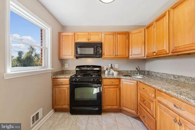 a kitchen with stainless steel appliances granite countertop a stove a sink and a microwave