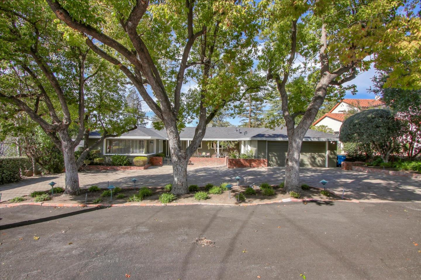 a front view of a house with a yard and large trees