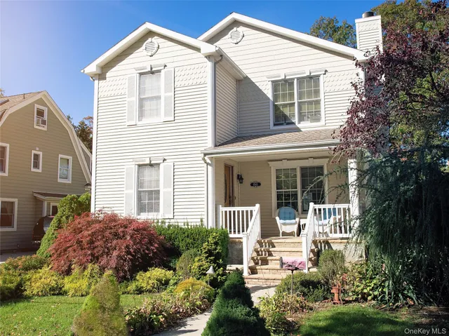 a view of a white house with a small yard and plants