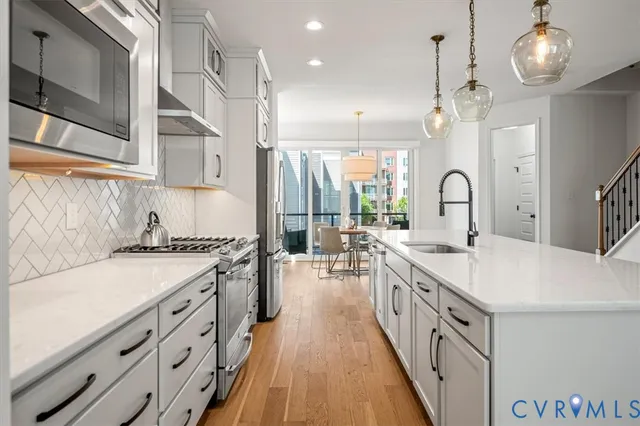a kitchen with a refrigerator a stove and white cabinets with wooden floor