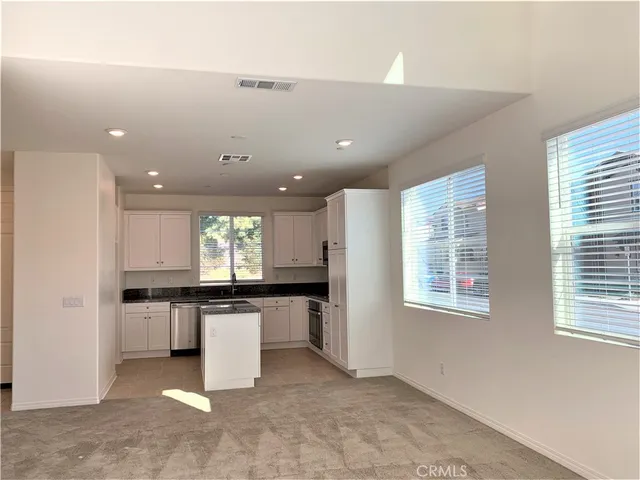 a kitchen with stainless steel appliances granite countertop a stove top oven a sink a dining table and chairs