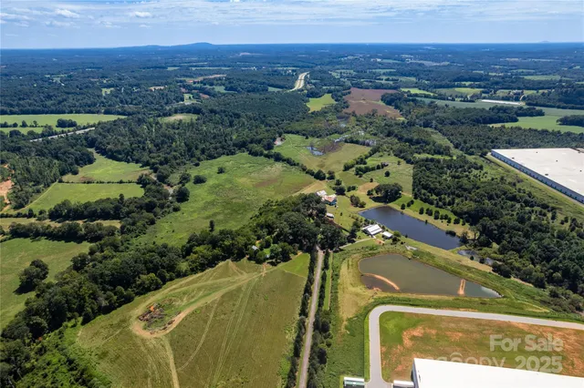 an aerial view of a residential houses with outdoor space and trees