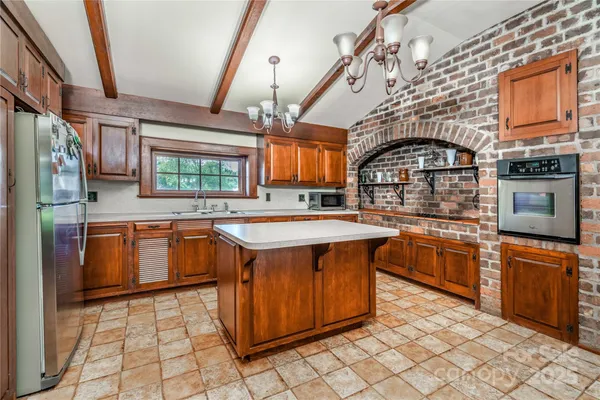 a kitchen with stainless steel appliances granite countertop a stove a sink dishwasher and wooden cabinets with wooden floor