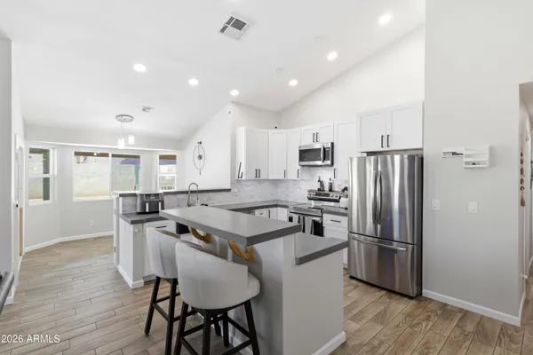 a kitchen with stainless steel appliances granite countertop a refrigerator a stove a sink a dining table and chairs