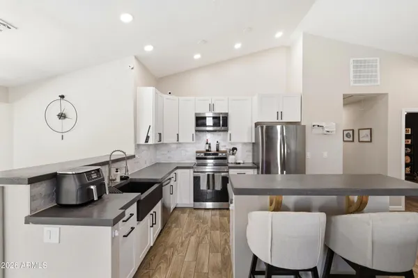 a kitchen with stainless steel appliances granite countertop a stove a sink a microwave a refrigerator and cabinets