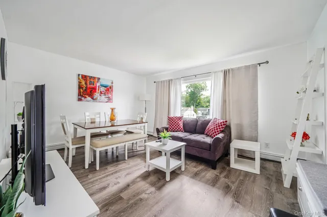 a living room with furniture a flat screen tv and a dining table with wooden floor