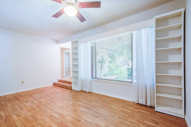 a view of an empty room with a window and wooden floor