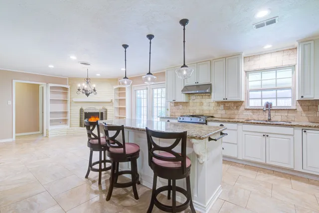 a kitchen with kitchen island a large window and chairs