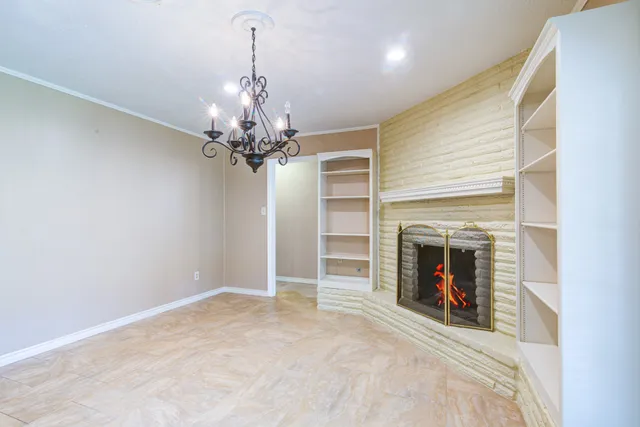 a view of a livingroom with a fireplace a chandelier and windows