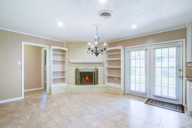 a view of an empty room with a fireplace and a window