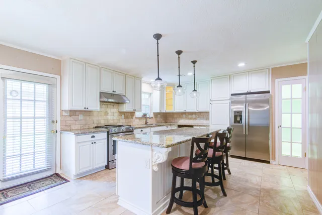 a kitchen with a dining table chairs wooden cabinets and refrigerator