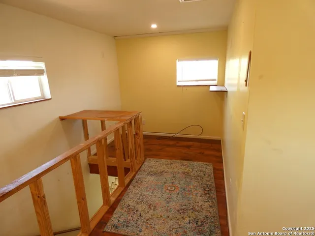 a view of a hallway with wooden floor and stairs