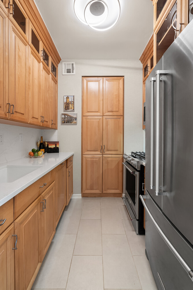 200 East 69th Street, Unit 16E Manhattan, NY 10021 - Photo 9 of 17 a kitchen with granite countertop a refrigerator and a sink