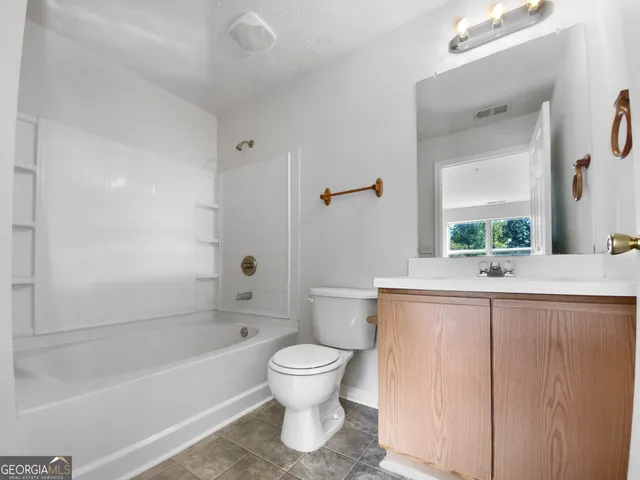 a bathroom with a granite countertop toilet a sink and a bathtub
