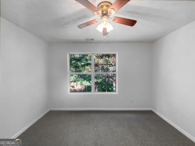 an empty room with a window and a fan