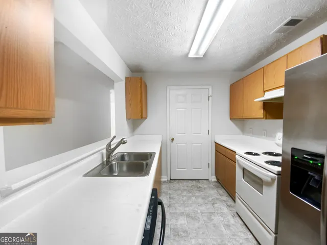 a kitchen that has a sink wooden cabinets and stainless steel appliances