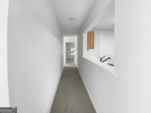 a view of a hallway with a white walls and wooden floor