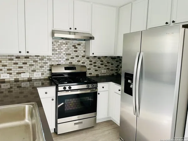 a kitchen with refrigerator a stove and a sink
