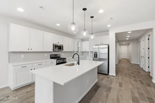 a large white kitchen with lots of counter space a sink appliances and cabinets