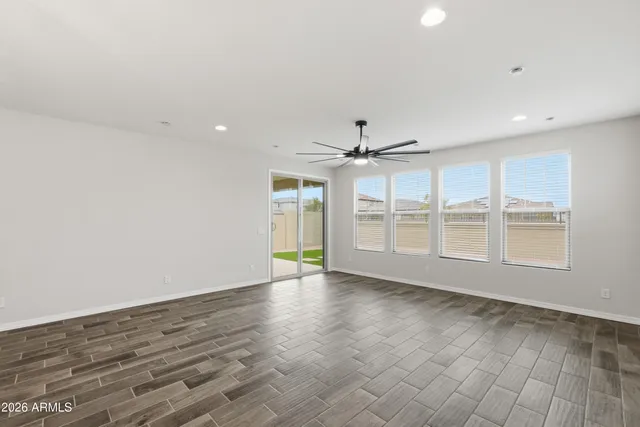 an empty room with wooden floor fan and windows