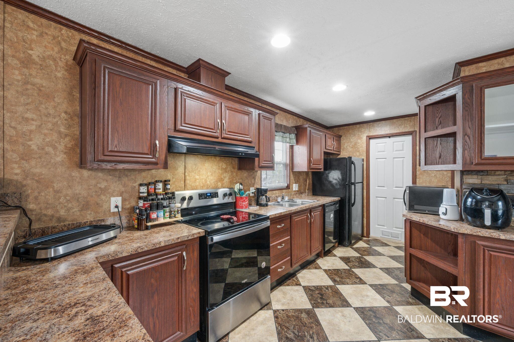 39908 T A Chastang Road Bay Minette, AL 36507 - Photo 7 of 20 Kitchen featuring light floors, under cabinet range hood, black appliances, open shelves, and a sink