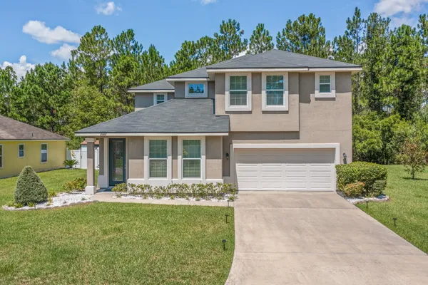a front view of a house with a yard and potted plants