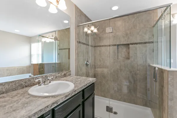 a bathroom with a granite countertop sink and a bathtub