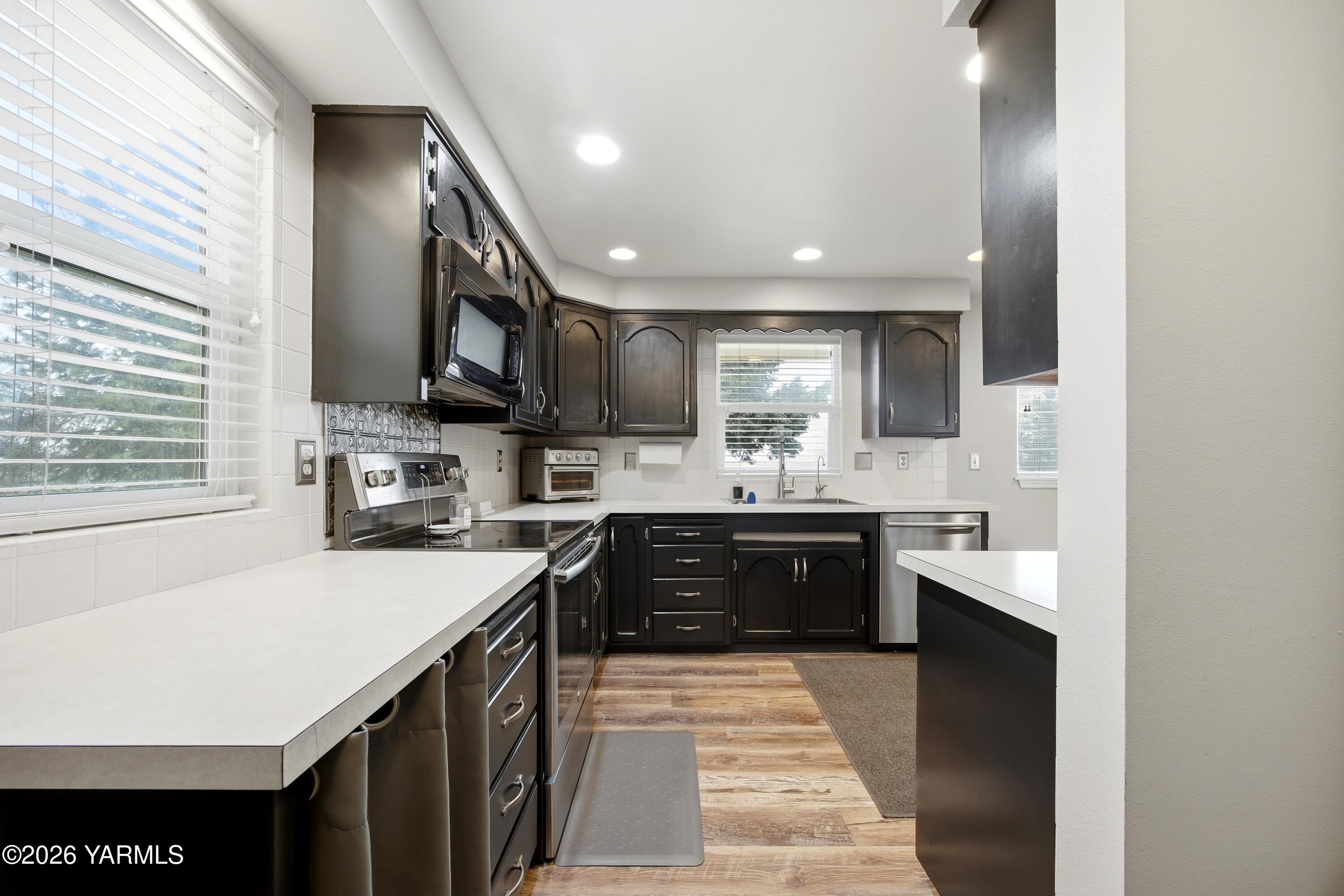 1681 Olmstead Road Grandview, WA 98930 - Photo 37 of 49 a large kitchen with stainless steel appliances kitchen island granite countertop a sink counter space cabinets and a couch