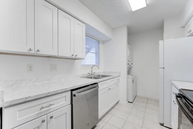 a kitchen with stainless steel appliances granite countertop a sink and dishwasher with white cabinets