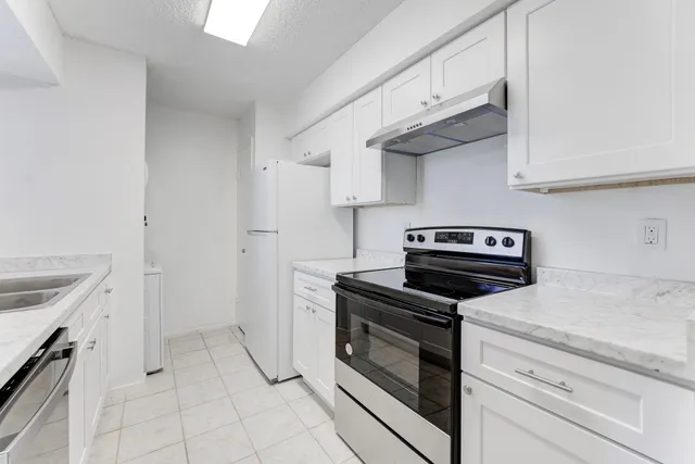 a kitchen with white cabinets and appliances