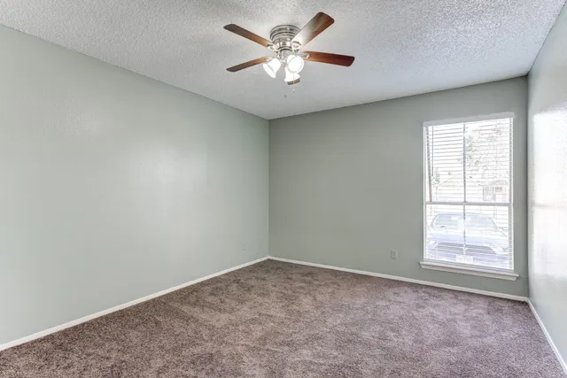 an empty room with windows and fan