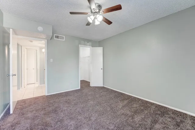 a view of an empty room and chandelier fan