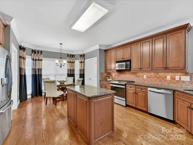 a kitchen with stainless steel appliances granite countertop wooden cabinets a refrigerator a stove a sink and a microwave