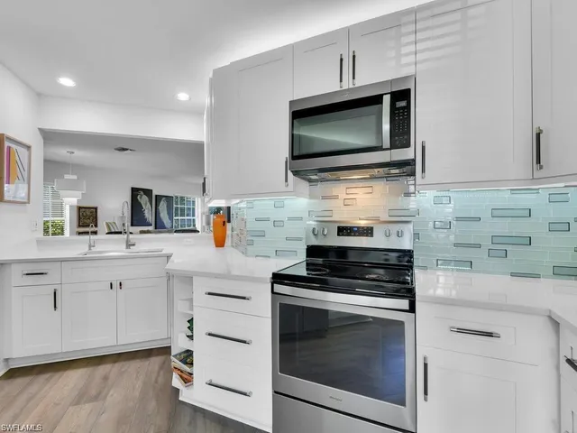 a kitchen with cabinets stainless steel appliances and wooden floor