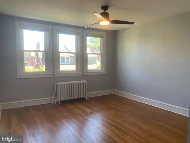 an empty room with wooden floor chandelier and windows