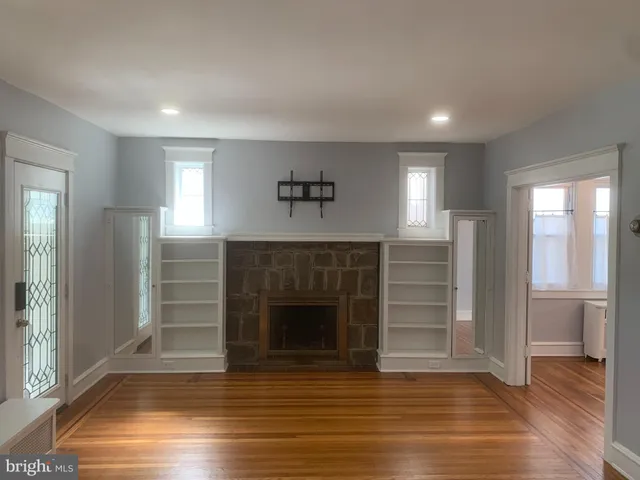 an empty room with wooden floor fireplace and windows