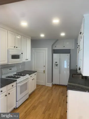 a kitchen with granite countertop a white stove top oven and cabinets