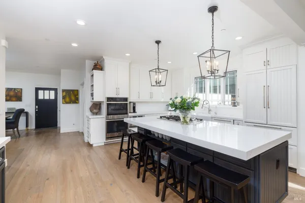 a kitchen with stainless steel appliances kitchen island granite countertop a table chairs and a refrigerator