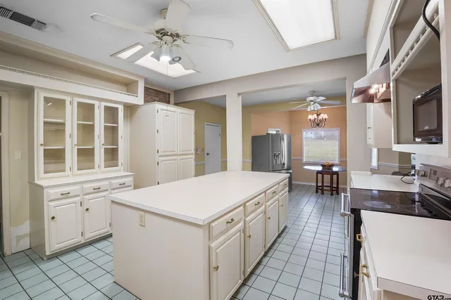 a large white kitchen with cabinets a island a stove a dining table and chairs