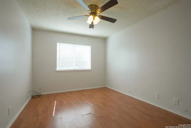 a view of a room with wooden floor and a ceiling fan