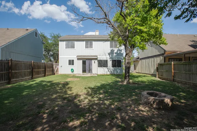 a view of a house with backyard and a tree